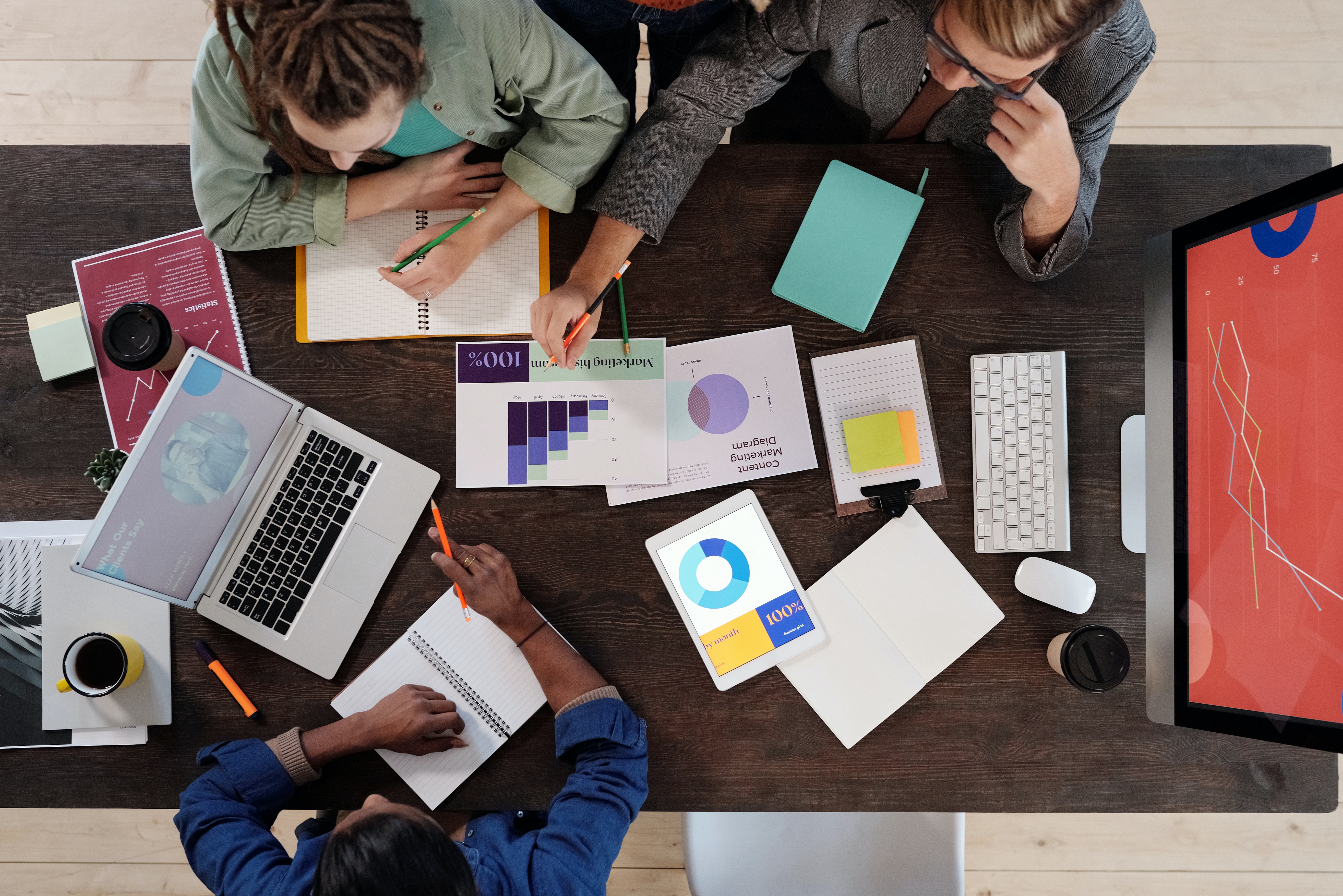 Three people looking over charts, graphs, and other paperwork in a business setting