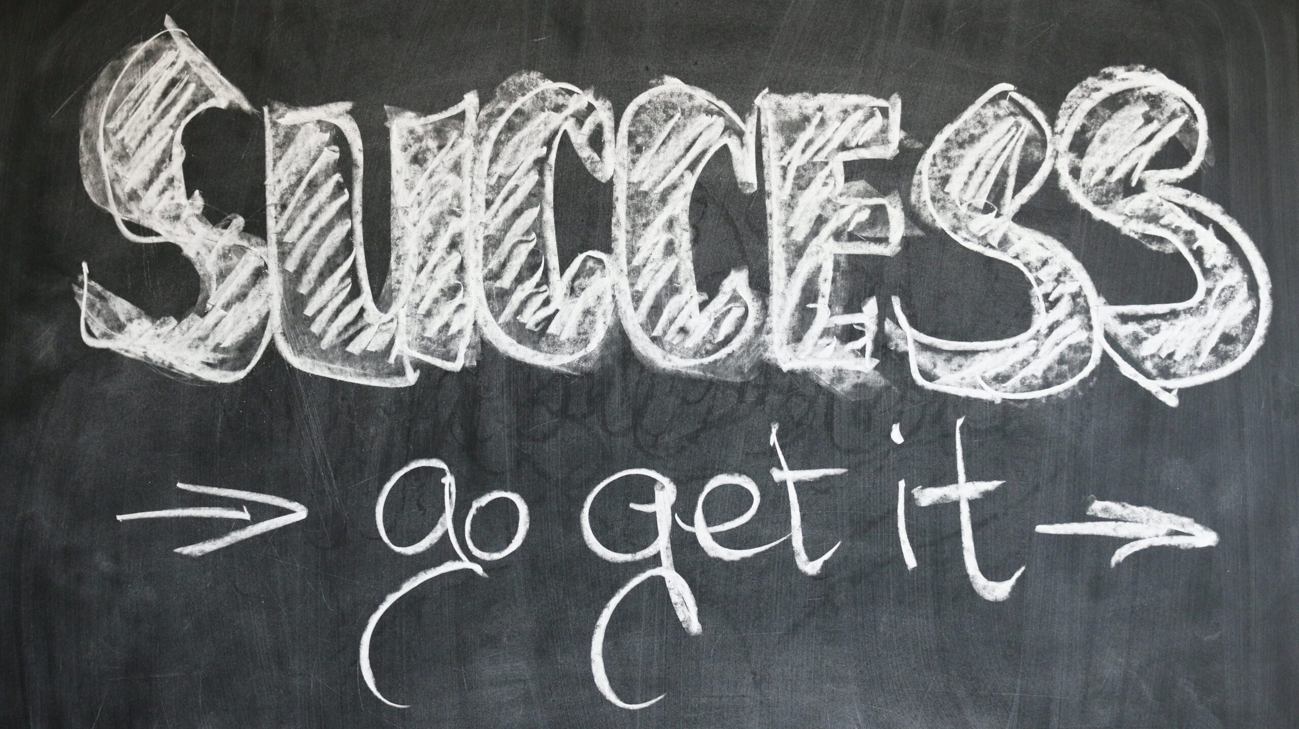A chalkboard sign that says Success Go Get It with two arrows pointing to the right 